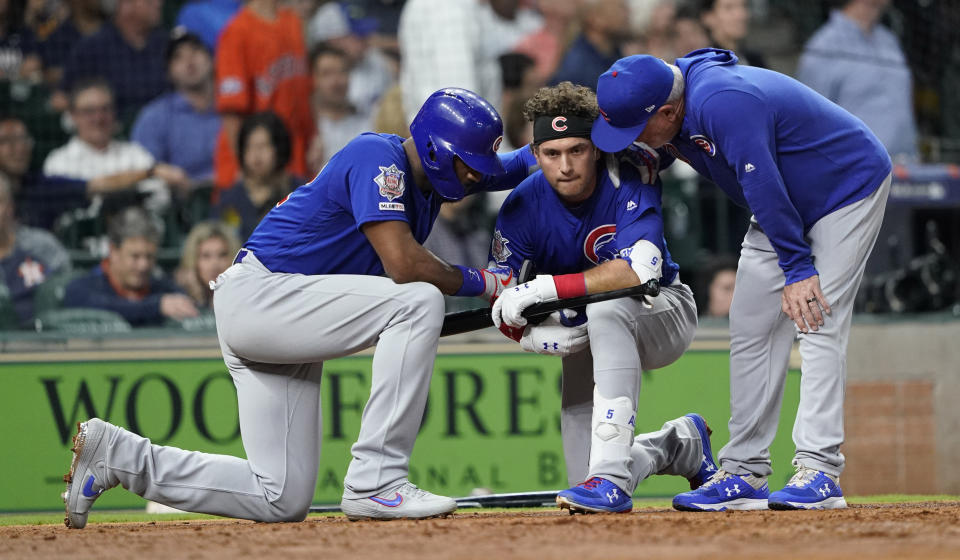 Arrodillado, Albert Almora Jr., de los Cachorros de Chicago, es consolado por su compañero Jason Heyward (izquierda) y por el manager Joe Maddon, después de que una pelota que había bateado de foul impactó a una niña en el graderío, durante el juego ante los Astros en Houston, el miércoles 29 de mayo de 2019 (AP Foto/David J. Phillip)