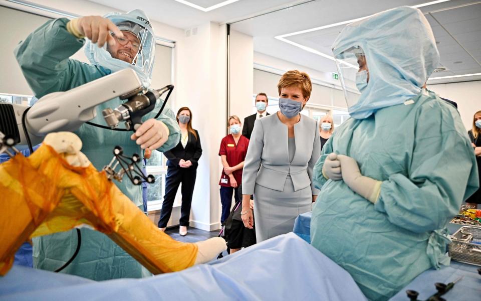 Scotland's First Minister Nicola Sturgeon gestures as she tours a mock theatre set up with innovative new medical equipment, including robotic surgery devices, during a visit to launch the NHS recovery plan at the new national Centre for Sustainable Delivery (CfSD) at the Golden Jubilee Hospital in Clydebank, Scotland - AFP 