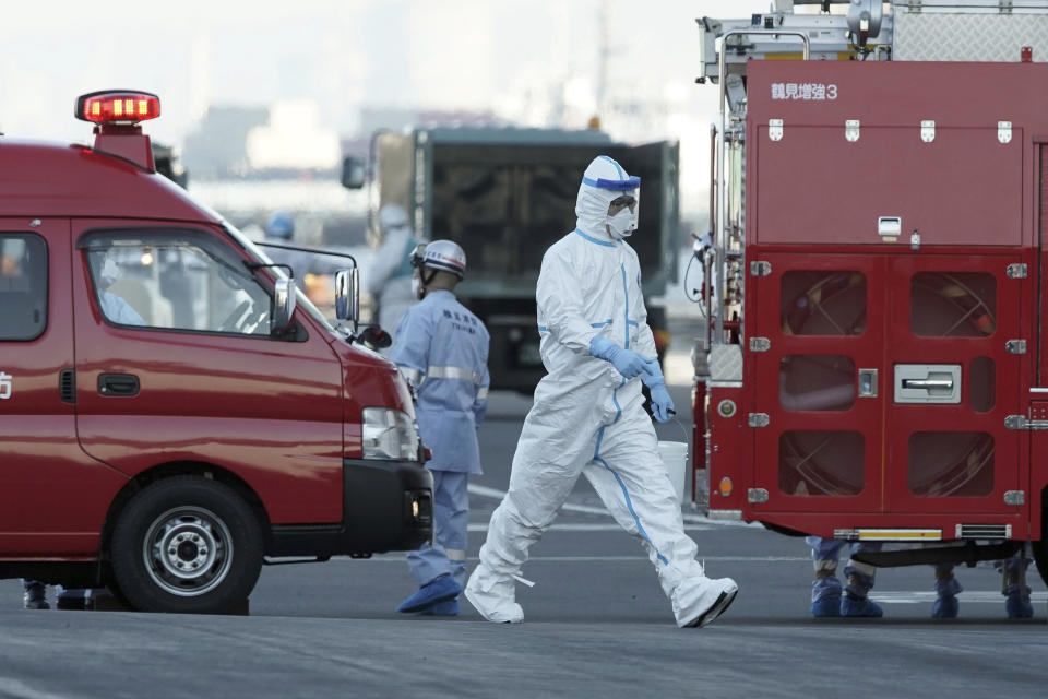 An official with protective suites walks near the cruise ship Diamond Princess anchored off the Yokohama Port in Yokohama, near Tokyo Monday, Feb. 10, 2020. China reported a rise in new virus cases on Monday, possibly denting optimism disease control measures that have isolated major cities might be working, while Japan reported dozens of new cases aboard the quarantined cruise ship. (AP Photo/Eugene Hoshiko)