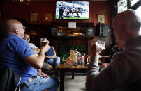 People enjoy their beers as they watch horse racing at the Forester pub in London, Saturday, July 4, 2020. England is embarking on perhaps its biggest lockdown easing yet as pubs and restaurants have the right to reopen for the first time in more than three months. In addition to the reopening of much of the hospitality sector, couples can tie the knot once again, while many of those who have had enough of their lockdown hair can finally get a trim. (AP Photo/Frank Augstein)