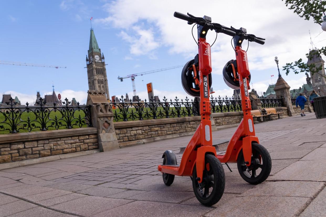Two Neuron e-scooters are parked near Parliament Hill in July 2022. Neuron is one of two companies that will be offering up scooters on the city's streets this year. (Francis Ferland/CBC - image credit)