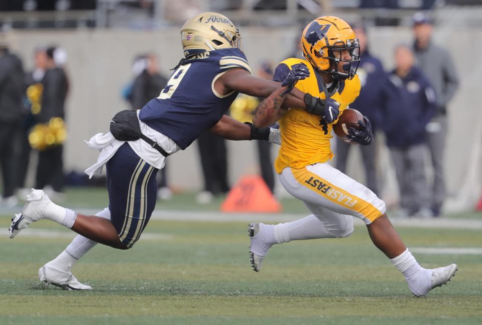 Kent State running back Marquez Cooper is caught from behind by Akron's Jeslord Boateng during a first-quarter run on Saturday, Nov. 20, 2021, in Akron, Ohio, at InfoCision Stadium.