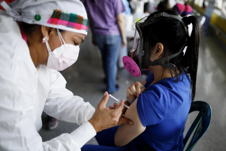 FILE - In this April 23, 2021, file photo, a health care worker inoculates Dr. Virma Rivas with the Sputnik V COVID-19 vaccine, as part of a vaccination campaign in Tegucigalpa, Honduras. Honduras has obtained a paltry 59,000 vaccine doses for its 10 million people. Similar gaps in vaccine access are found across Africa, where just 36 million doses have been acquired for the continent's 1.3 billion people, as well as in parts of Asia. (AP Photo/Elmer Martinez, File)