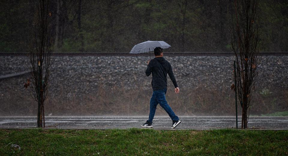 A pedestrian walked along Dixie Highway under an umbrella as rain fell Friday afternoon. Mar. 3, 2023