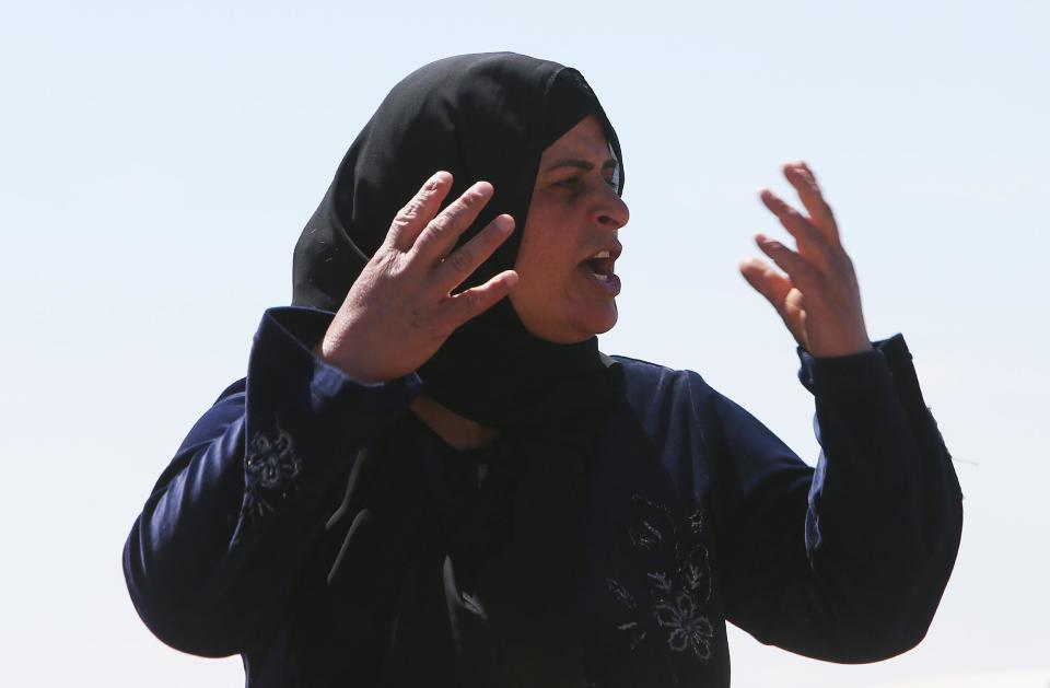 A Lebanese woman who fled her house from the Lebanese-Syrian border village of Tfail, reacts as she stands on the top of a pickup on her way back home, in Ras al-Haref, which leads to Tfail village in eastern Lebanon, Tuesday April 22, 2014. A Lebanese convoy of soldiers, clerics and Red Cross officials delivered aid Tuesday to a remote village near the Syrian border that was bombed by Syrian government aircraft and blocked by Lebanese militants fighting alongside President Bashar Assad’s forces in the civil war next door. Hezbollah fighters have been patrolling the area on the Lebanese side and fighting has flared up inside Syria, cutting Tfail’s residents off from all sides for months. (AP Photo/Hussein Malla)