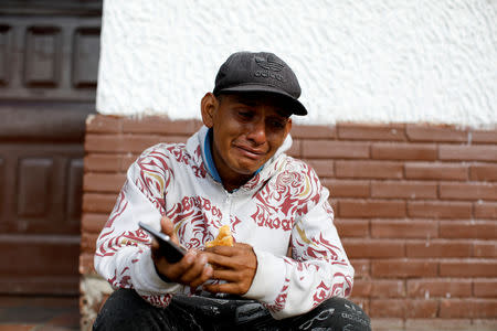 FILE PHOTO: Luis Pena, an undocumented Venezuelan migrant, cries after he received a voice message from his mother on the cellphone of a travel companion, while resting next to the road between Pamplona and La Laguna, near Mutiscua, Colombia August 28, 2018. REUTERS/Carlos Garcia Rawlins/File Photo