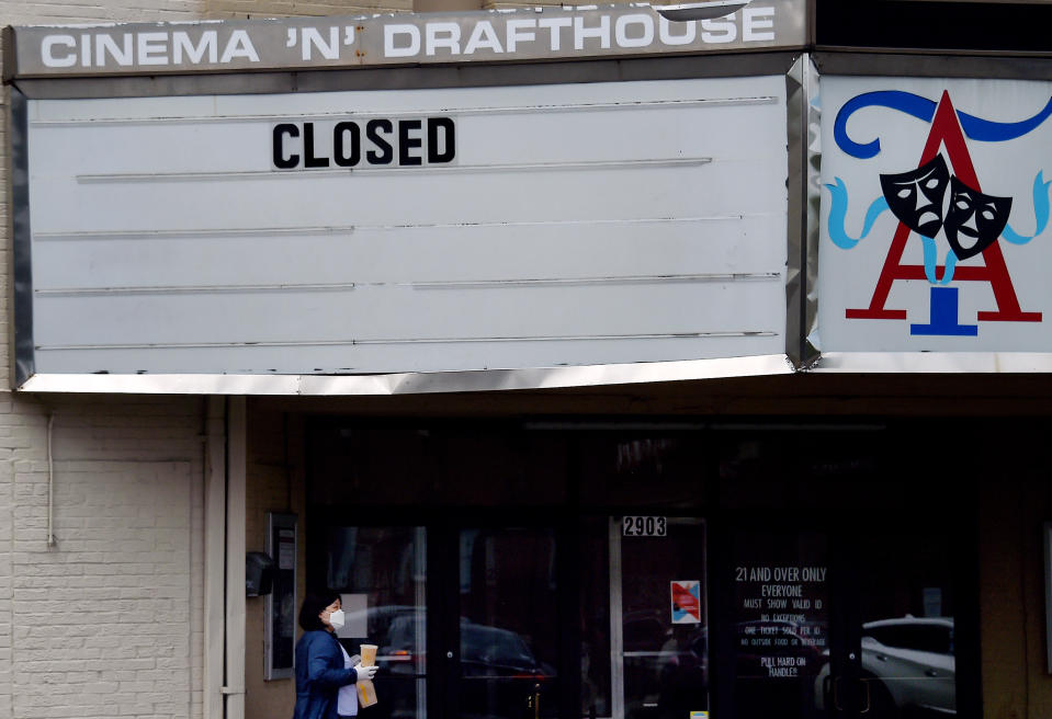 A woman wearing a face mask walks past the closed Arlington Cinema and Drafthouse movie theater amid the coronavirus pandemic on May 14, 2020 in Arlington, Virginia. - Another 3 million people filed initial unemployment claims last week on a seasonally adjusted basis, according to the Department of Labor. (Photo by Olivier DOULIERY / AFP) (Photo by OLIVIER DOULIERY/AFP via Getty Images)