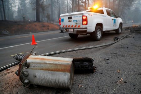 An electricity pole damaged by the Camp Fire lies near a Pacific Gas & Electric (PG&E) truck in Paradise, California, U.S., November 14, 2018.  REUTERS/Terray Sylvester