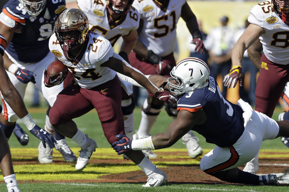 Minnesota running back Mohamed Ibrahim (24) slips a tackle by Auburn defensive end Marlon Davidson (3) during the first half of the Outback Bowl NCAA college football game Wednesday, Jan. 1, 2020, in Tampa, Fla. (AP Photo/Chris O'Meara)