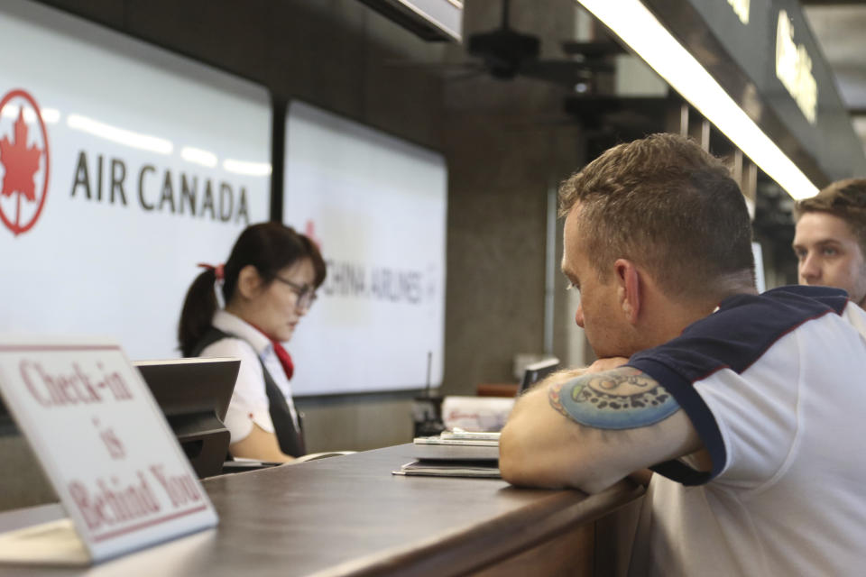 Andrew Szucs, right, who was on the Air Canada flight that made an emergency landing, waits for assistance at the Air Canada desk, Thursday, July 11, 2019 at Honolulu's international airport. Intense turbulence struck an Air Canada flight to Australia on Thursday and sent unbuckled passengers flying into the ceiling, leaving about 35 people with minor injuries and forcing the plane to land in Hawaii. (AP Photo/Caleb Jones)