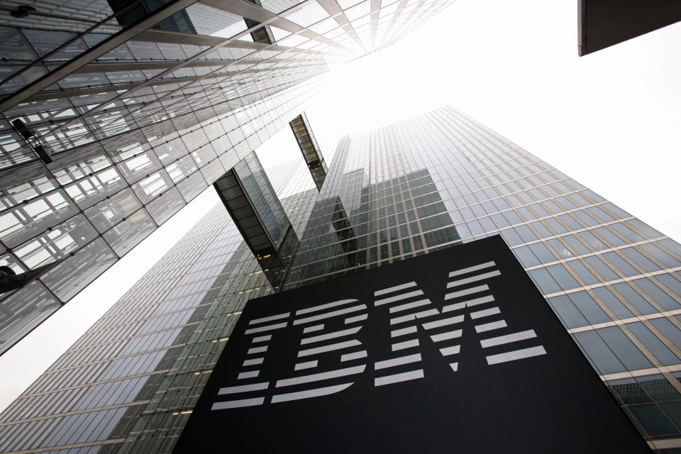 Photo taken upward from the foot of a tall, glass-clad office building, highlighting a large IBM logo.