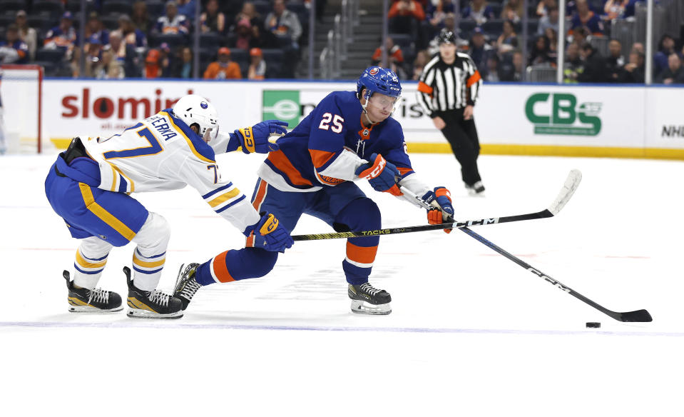 New York Islanders defenseman Sebastian Aho (25) plays the puck against Buffalo Sabres right wing JJ Peterka (77) during the second period of an NHL hockey game, Saturday, Oct. 14, 2023, in New York. (AP Photo/Noah K. Murray)