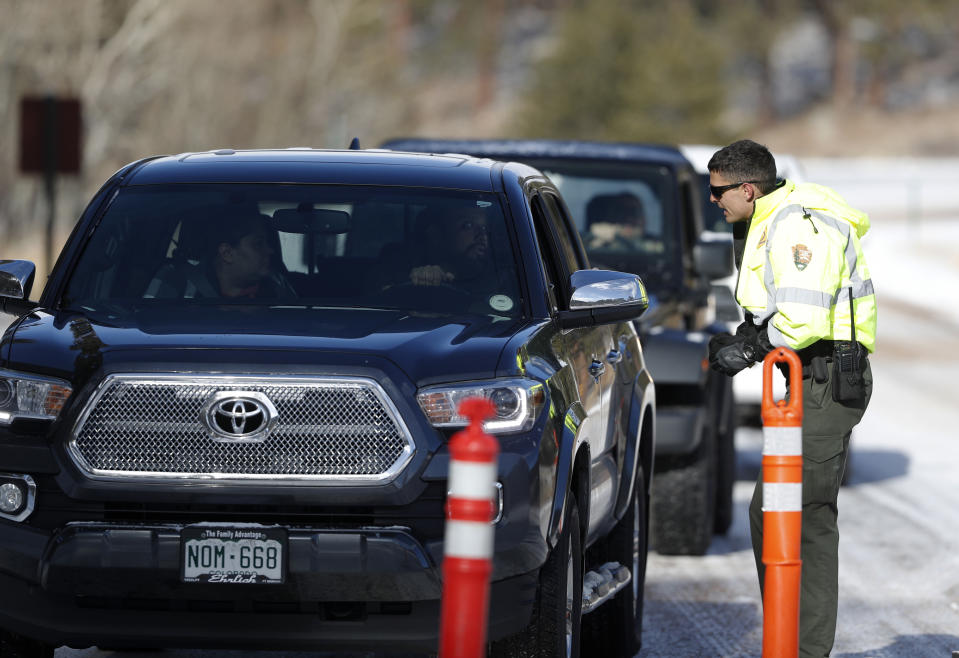 Park ranger Dillon O'Brien stops motorists as they try to navigate the snow packed road to Bear Lake in Rocky Mountain National Park Saturday, Dec. 22, 2018, in Estes Park, Colo. Some roads in the park were left unplowed after an overnight snow because a partial federal shutdown. (AP Photo/David Zalubowski)