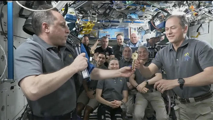 Outgoing space station commander Anton Shkaplerov, left, hands a symbolic key to the space station to NASA astronaut Thomas Marshburn Tuesday in a traditional change-of-command ceremony. Shkaplerov, cosmonaut Pyotr Dubrov (to immediate left of key in background) and NASA astronaut Mark Vande Hei (to right of key) plan to return to Earth Wednesday. / Credit: NASA TV