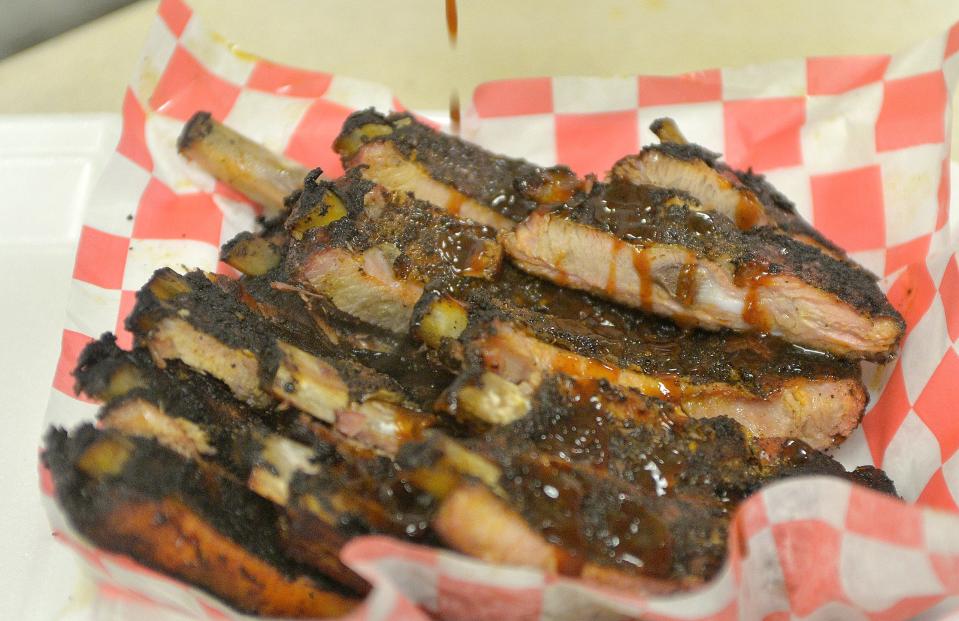 Sauce is drizzled on ribs at Zoo's BBQ in Millcreek Township, which opened in August.