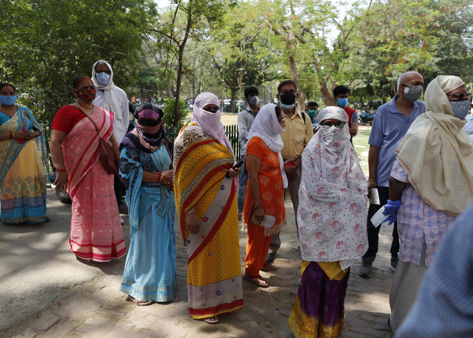 Indians cover their faces as a precaution against the coronavirus line up to receive the vaccine for COVID-19 at a medical college in Prayagraj, India, Saturday, May 8, 2021. Two southern states in India became the latest to declare lockdowns, as coronavirus cases surge at breakneck speed across the country and pressure mounts on Prime Minister Narendra Modi's government to implement a nationwide shutdown. (AP Photo/Rajesh Kumar Singh)