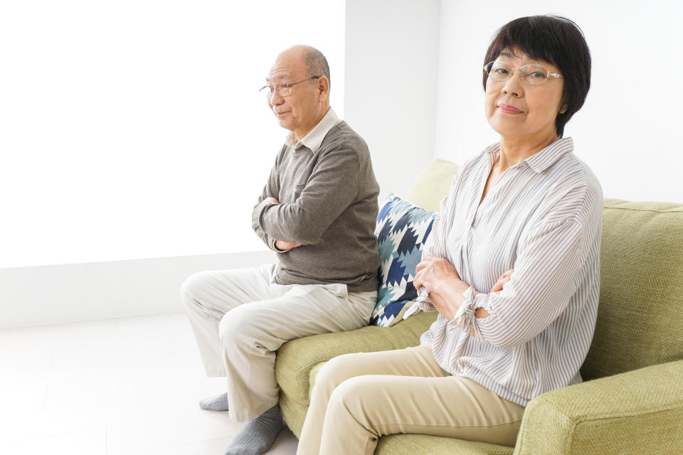 a couple witting on a couch with their arms crossed and not looking at one another