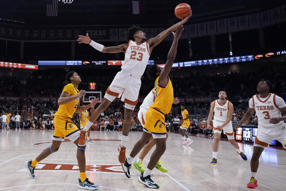 Texas forward Dillon Mitchell (23) reaches over UNC Greensboro forward Jalen Breath for a rebound during the first half of an NCAA college basketball game in Austin, Texas, Friday, Dec. 29, 2023. (AP Photo/Eric Gay)