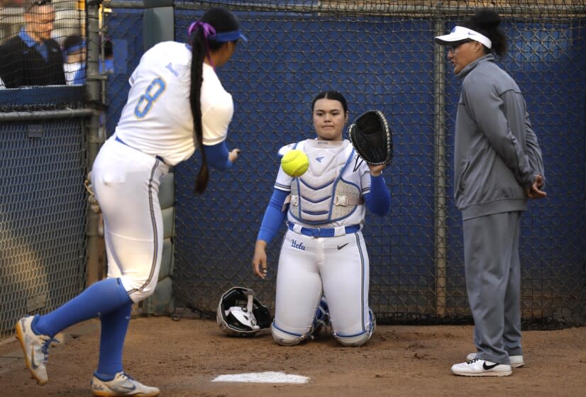 LOS ANGELES, CA - APRIL 29, 2022 - - UCLA softball pitcher Megan Faraimo warms up with catcher Taylor Sullivan as pitching coach Lisa Fernandez observes in the bullpen at Easton Stadium on the UCLA campus on April 29, 2022. Pitching coach Fernandez is a three-time Olympic Gold Medalist. (Genaro Molina / Los Angeles Times)
