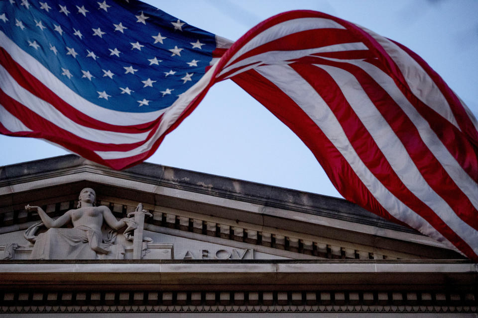 FILE - In this March 22, 2019 file photo, an American flag flies outside the Department of Justice in Washington. The FBI, in a change of policy, is committing to inform state officials if local election systems have been breached, federal officials told The Associated Press. (AP Photo/Andrew Harnik)