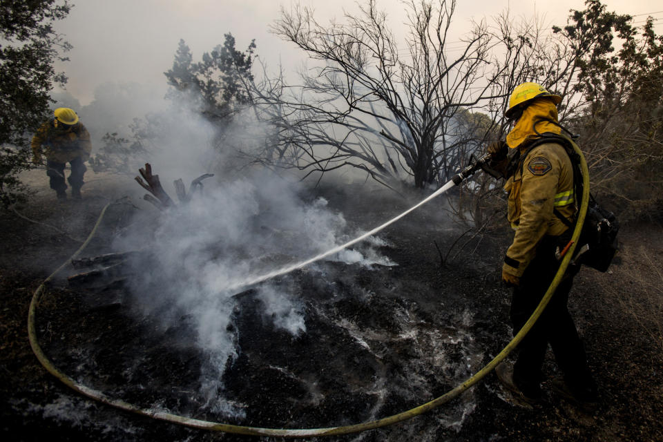 ARCHIVO - En esta foto de archivo del 18 de septiembre de 2020, los bomberos trabajan para sofocar los puntos calientes de un incendio en Juniper Hills, California. El viernes 25 de septiembre de 2020, The Associated Press informó sobre historias que circulan en línea afirmando incorrectamente que imágenes de los bomberos tomadas en otros países o en otros años mostraban a los bomberos luchando contra los actuales incendios en California. (AP Foto/ Ringo H.W. Chiu, archivo)