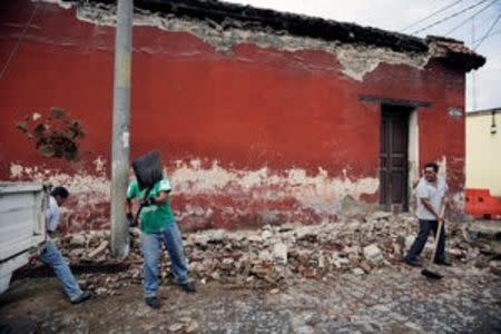 Municipal workers remove debris from a damaged house after an earthquake in Antigua, Guatemala June 22, 2017. REUTERS/Luis Echeverria