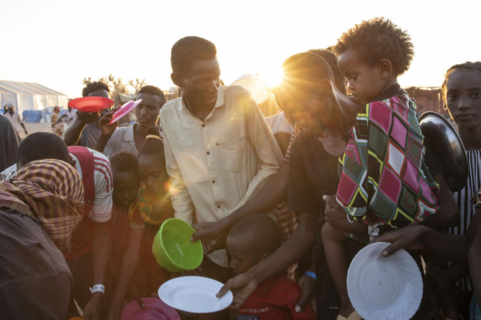 Tigray refugees who fled the conflict in Ethiopia's Tigray region, wait to get cooked rice served by Sudanese local volunteers at Um Rakuba refugee camp in Qadarif, eastern Sudan, Monday, Nov. 23, 2020. Tens of thousands of people have fled a conflict in Ethiopia for Sudan, sometimes so quickly they had to leave family behind. There is not enough to feed them in the remote area of southern Sudan that they rushed to. (AP Photo/Nariman El-Mofty)