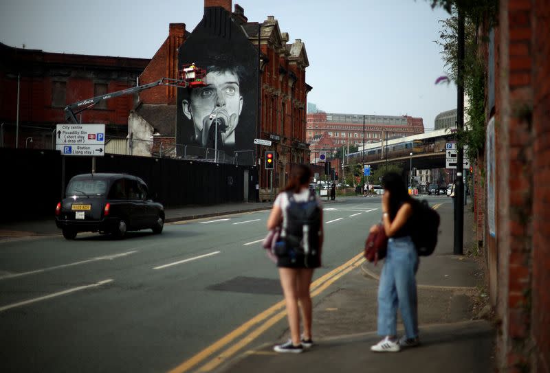 Artist Akse P19 works on a mural of singer Ian Curtis of Joy Division in Manchester