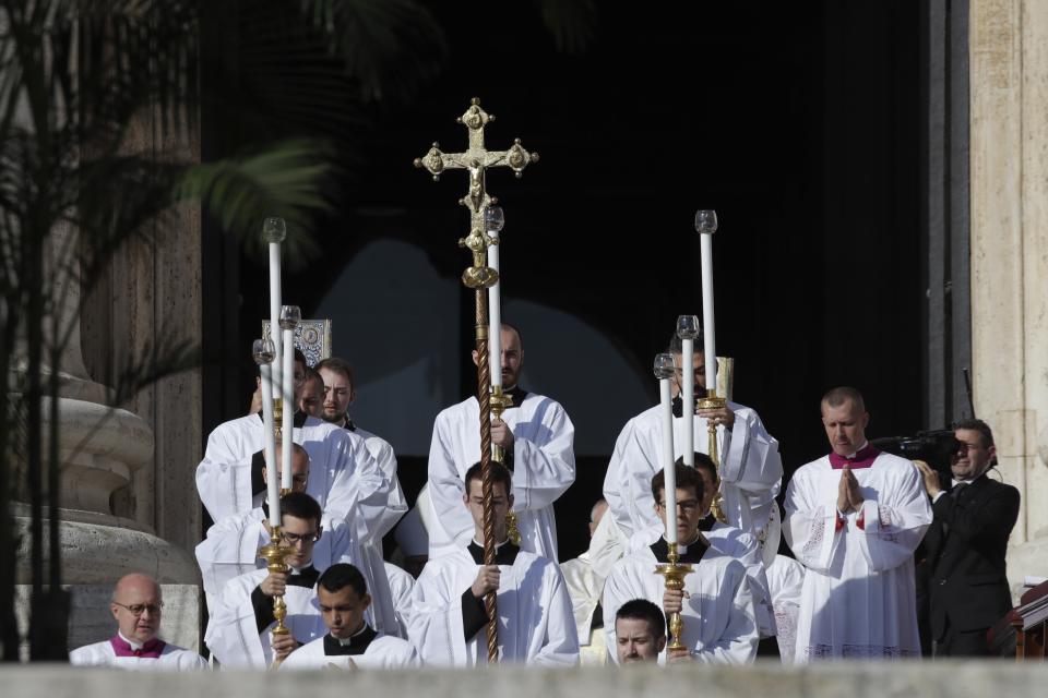 Priests hold candles and a crucifix during a canonization Mass in St. Peter's Square at the Vatican, Sunday, Oct. 13, 2019. Pope Francis canonizes Cardinal John Henry Newman, the 19th century Anglican convert who became an immensely influential thinker in both Anglican and Catholic churches, and four other women. (AP Photo/Alessandra Tarantino)