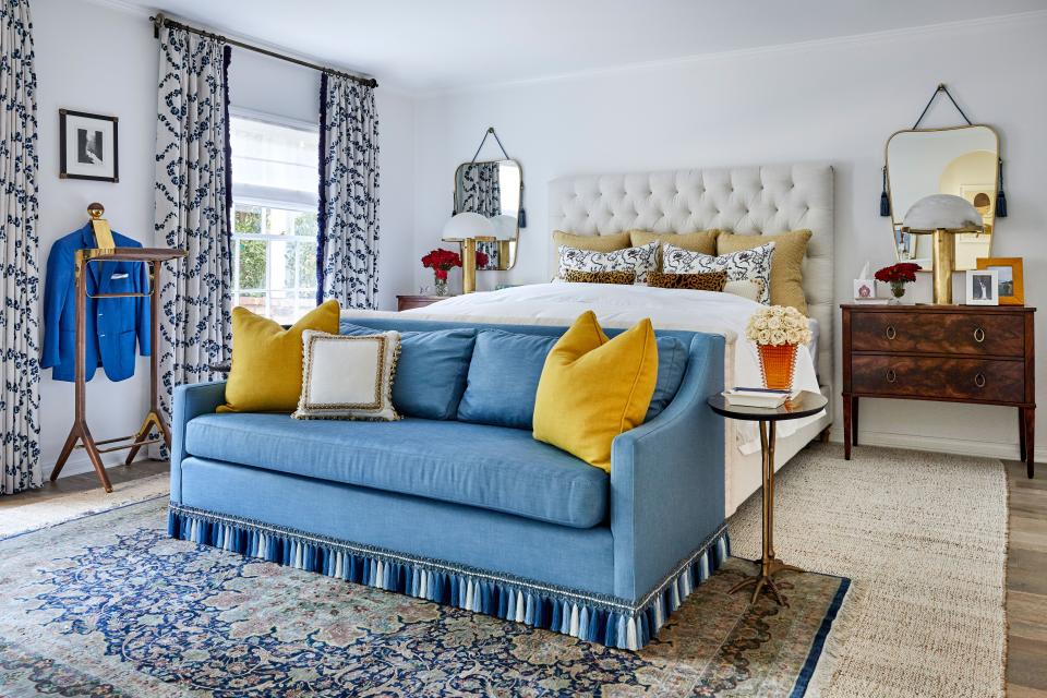 Pops of Bijan yellow add to the primary bedroom’s blue scheme, with an inherited Persian silk carpet, custom sofa (with Osborne & Little tassel trim), Kelly Wearstler for Visual Comfort lamps, and an Honorific valet stand.