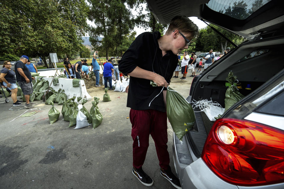 Jaden Fitzpatrick, 16, loads sandbags into their SUV at Wildwood Park in San Bernardino, Ca., on Saturday, Aug. 19, 2023, in preparation for the impending arrival of Hurricane Hillary. (Watchara Phomicinda/The Orange County Register via AP)