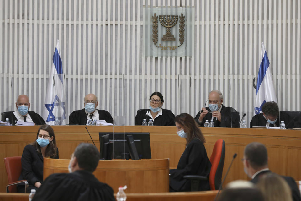 A panel of 11 Israeli Supreme Court judges with face masks hear arguments against the legality of Prime Minister Benjamin Netanyahu’s coalition deal with his former rival, Benny Gantz, at the Israeli Supreme Court in Jerusalem, Monday, May 4, 2020. (Abir Sultan/Pool via AP)