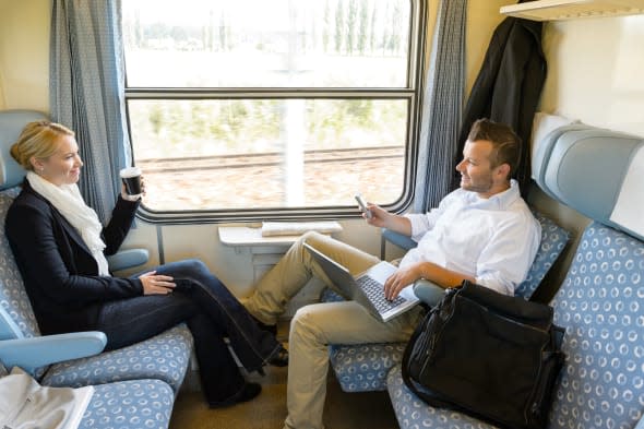 Man and woman sitting in train talking smiling commuters friends