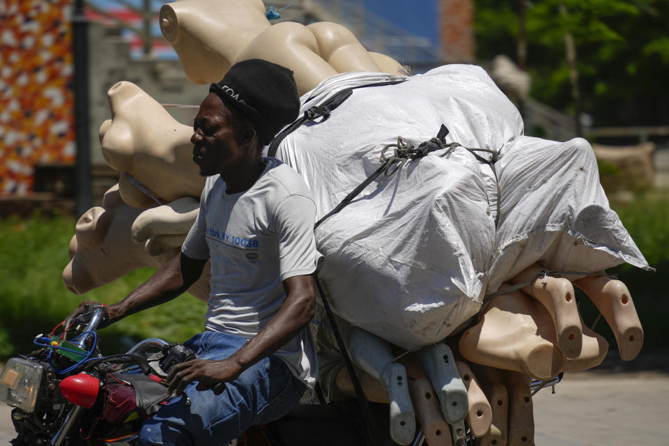A street vendor drives away his mannequins after gunshots broke out near the National Palace in Port-au-Prince, Haiti, Tuesday, April 30, 2024. (AP Photo/Ramon Espinosa)
