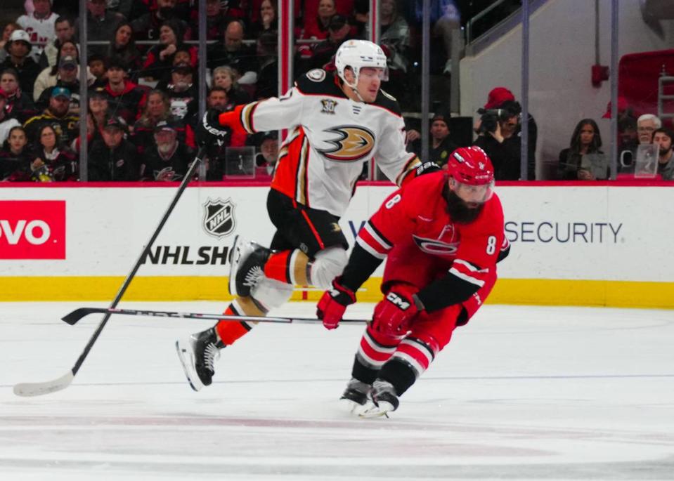 Jan 11, 2024; Raleigh, North Carolina, USA; Anaheim Ducks right wing Frank Vatrano (77) side steps a check by Carolina Hurricanes defenseman Brent Burns (8) during the second period at PNC Arena. Mandatory Credit: James Guillory-USA TODAY Sports