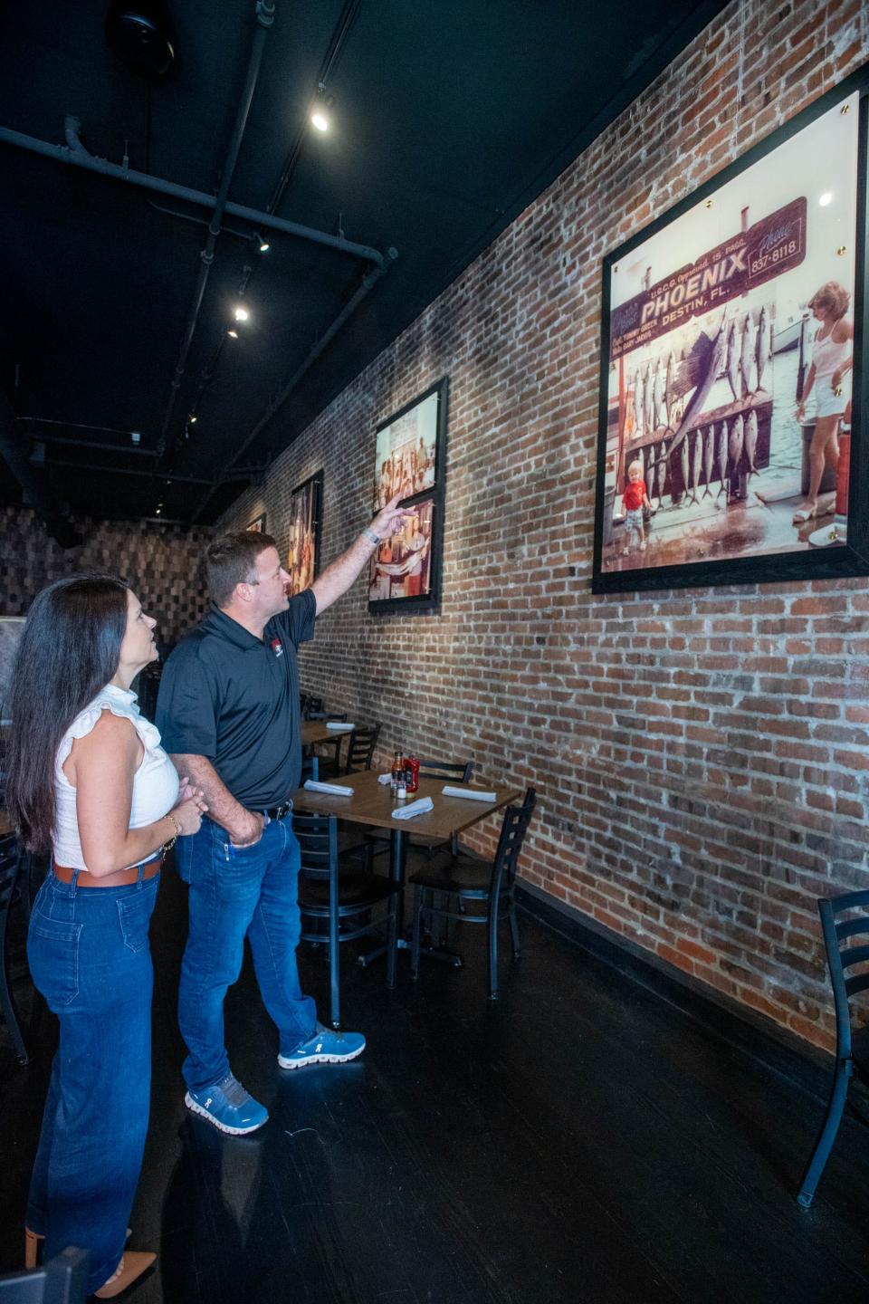 Owners Miranda and Bryce Jarvis talk about the vintage family photos displayed at Slick Lips Seafood & Oyster House restaurant on Palafox Place in downtown Pensacola on Thursday, Aug. 10, 2023.