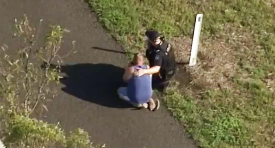 A man is consoled by police at the edge of the crash scene. Source: 7 News