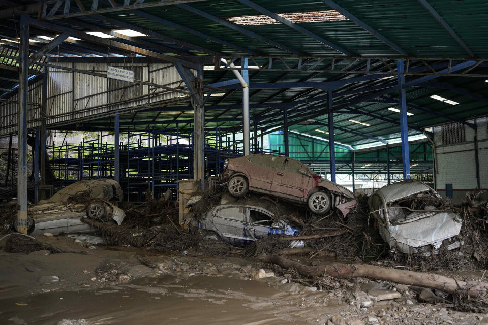 Varios automóviles yacen apliados en un taller luego de que intensas lluvias provocaron inundaciones repentinas y el desbordamiento del río Las Tejerías, el domingo 9 de octubre de 2022, en Las Tejerías, Venezuela. (AP Foto/Matías Delacroix)