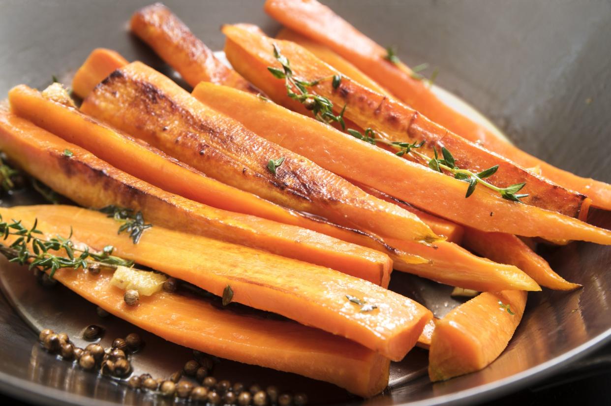 roasted carrots with thyme, coriander seed and honey in a wok pan,  recipe for root vegetables, selected focus, narrow depth of field