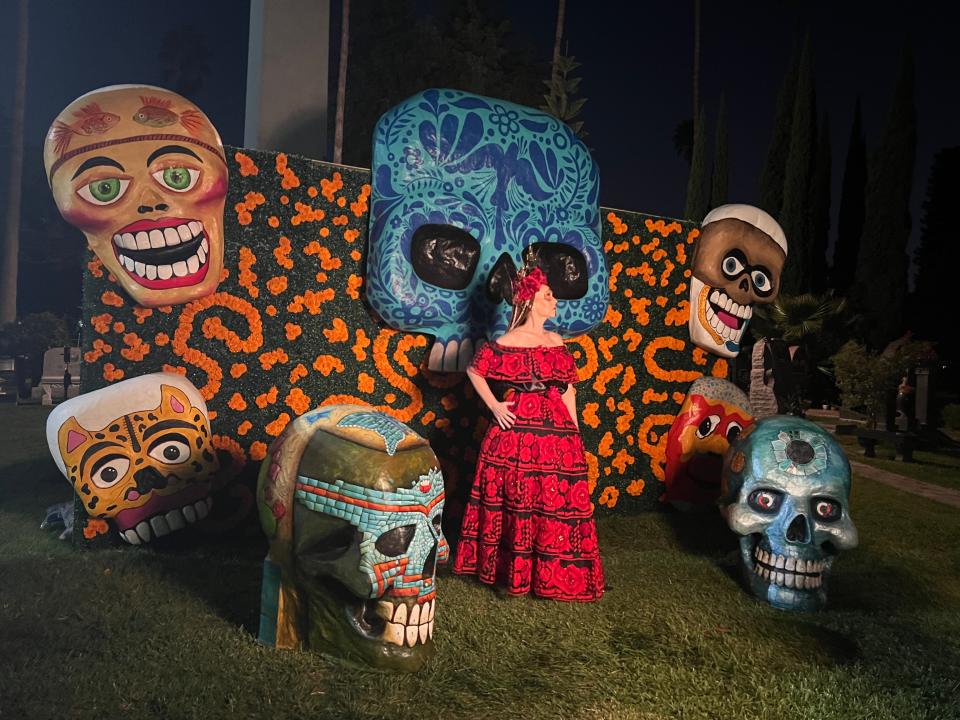 A woman poses with elaborate skeletons at the Día de Los Muertos celebration at the Hollywood Forever Cemetery in Los Angeles on Saturday, Oct. 28, 2023.