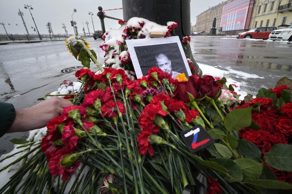 A man lays flowers near the site of an explosion at the "Street Bar" cafe in St. Petersburg, Russia, Monday, April 3, 2023. Russian police have arrested a woman suspected of delivering a bomb that killed well-known military blogger Vladlen Tatarsky on Sunday. Over 30 people were wounded by the blast. Russian news reports said the bomb was hidden in a bust of the blogger that the suspect had given to him as a gift just before the explosion. (AP Photo/Dmitri Lovetsky)
