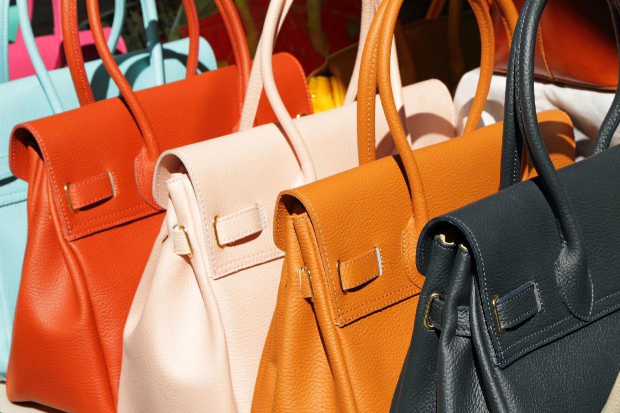 Five colorful leather purses in line for sale at San Lorenzo Market in Florence, Italy, other purses in background