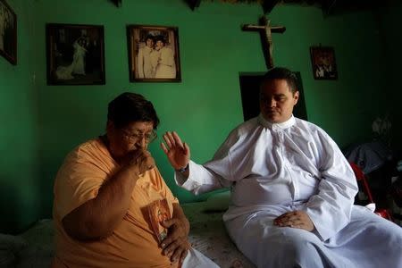 An aspiring Catholic priest Jose Luis Guerra, a member of Raza Nueva in Christ, a project of the archdiocese of Monterrey, blesses a woman with diabetes at her home in Monterrey, Mexico, July 13, 2016. REUTERS/Daniel Becerril