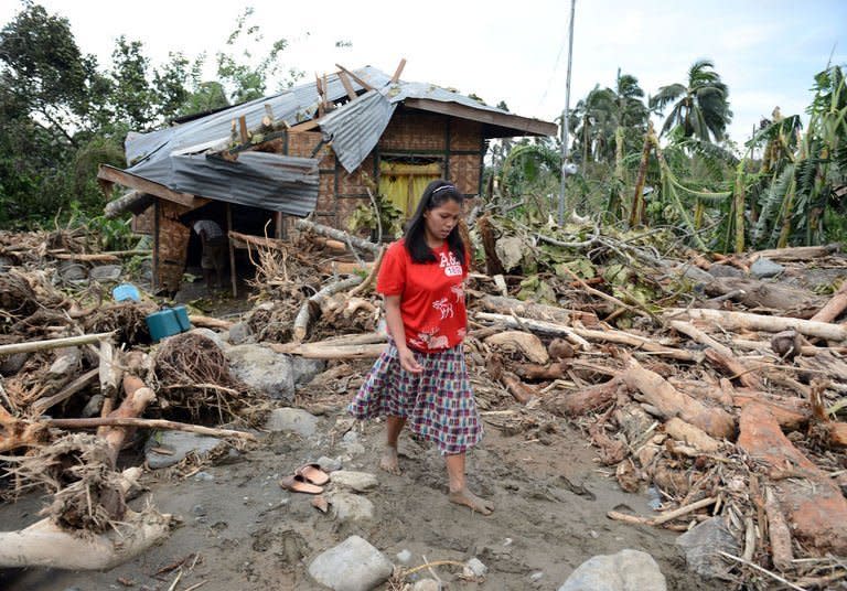 A woman walks amongst debris next to her damaged house in the village of Andap. The death toll from a typhoon that ravaged the Philippines jumped to 274 Wednesday with hundreds more missing, as rescuers battled to reach areas cut off by floods and mudslides