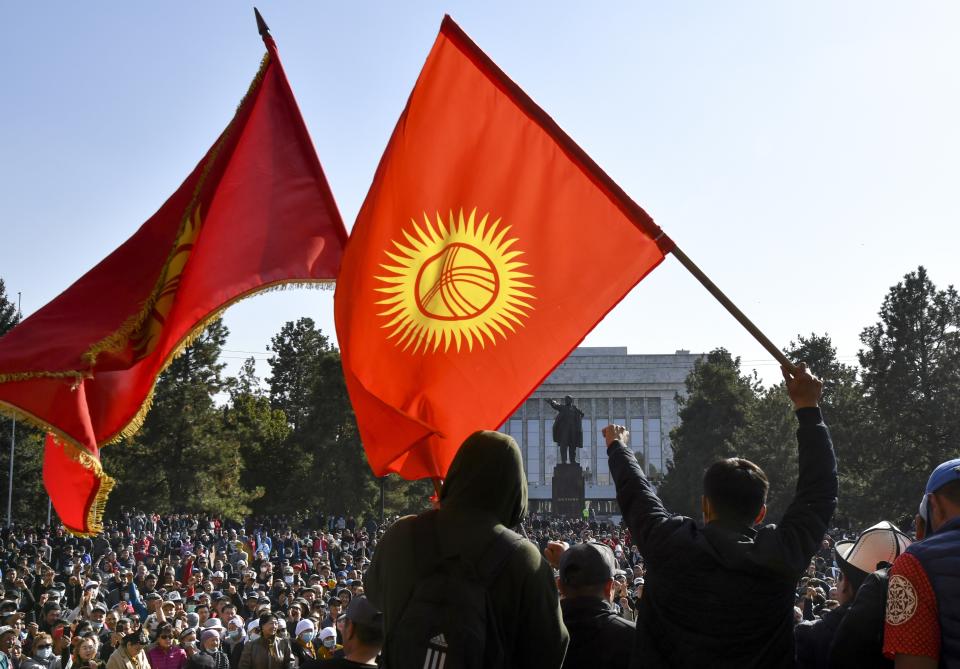 Protesters react waving Kyrgyz national flags as they wait for Kyrgyz Prime Minister Sadyr Zhaparov speech in front of the government building in Bishkek, Kyrgyzstan, Wednesday, Oct. 14, 2020. Kyrgyzstan's embattled president has discussed his possible resignation with his newly appointed prime minister in a bid to end the political crisis in the Central Asian country after a disputed parliamentary election. President Sooronbai Jeenbekov held talks with Prime Minister Sadyr Zhaparov a day after refusing to appoint him to the post over concerns whether parliament could legitimately nominate him. (AP Photo/Vladimir Voronin)