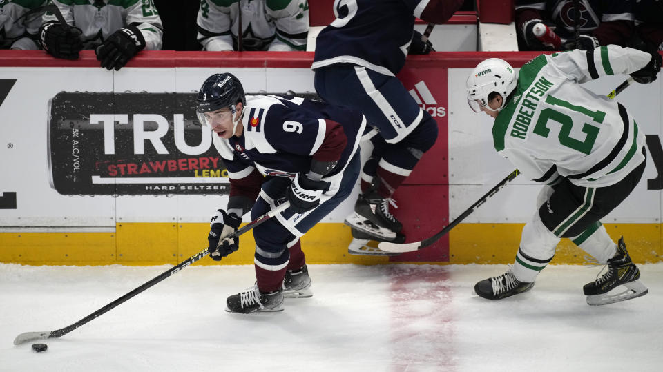 Colorado Avalanche center Evan Rodrigues, left, moves the puck as Dallas Stars left wing Jason Robertson defends in the first period of an NHL hockey game Saturday, April 1, 2023, in Denver. (AP Photo/David Zalubowski)