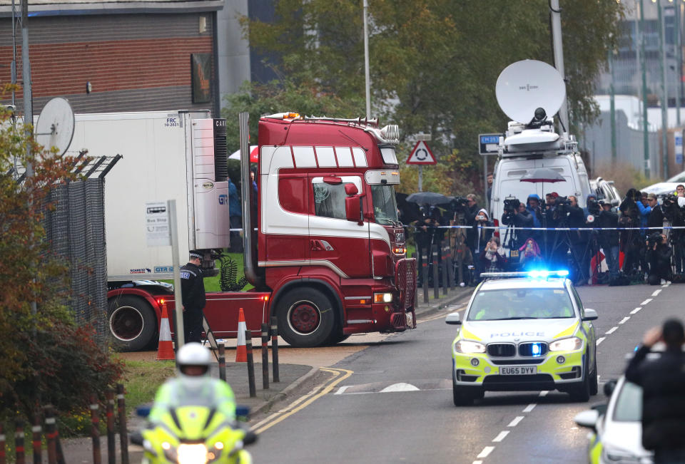 Media stand behind a police cordon as the lorry is moved from the Grays industrial estate shortly before 5pm on Wednesday. (PA)