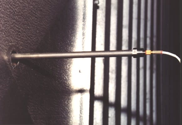 Metal leak-detecting rod stuck into an opening in a metal plate.