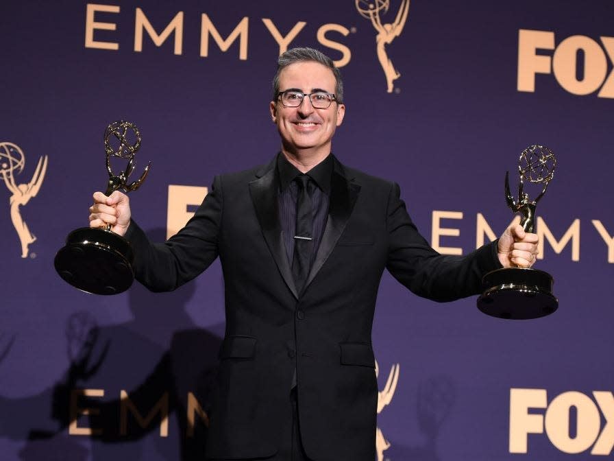 John Oliver holds Emmy awards in each hand at the 2019 Emmys.