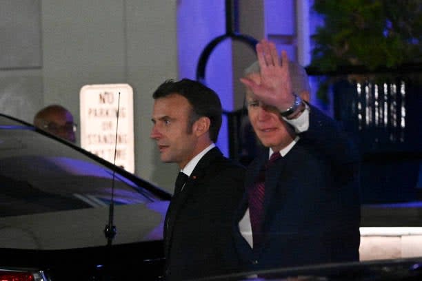 US president Joe Biden waves as he and French president Emmanuel Macron leave Fiola Mare restaurant after a private dinner in Washington, DC, on 30 November 2022 (AFP via Getty Images)